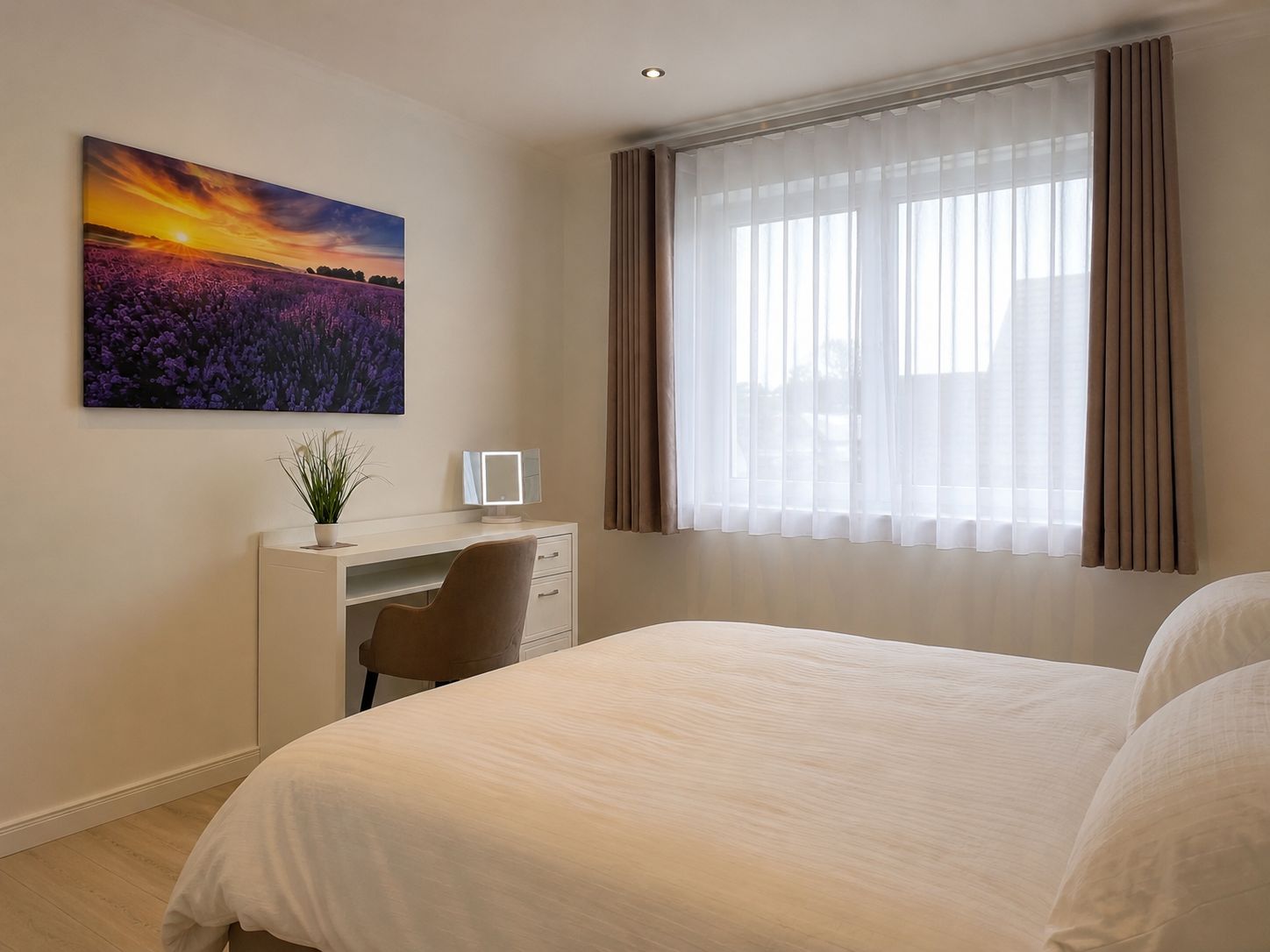 Ein Hotelzimmer mit Bett, Schreibtisch mit Stuhl, Spiegel und einem großen Fenster mit Vorhängen.
