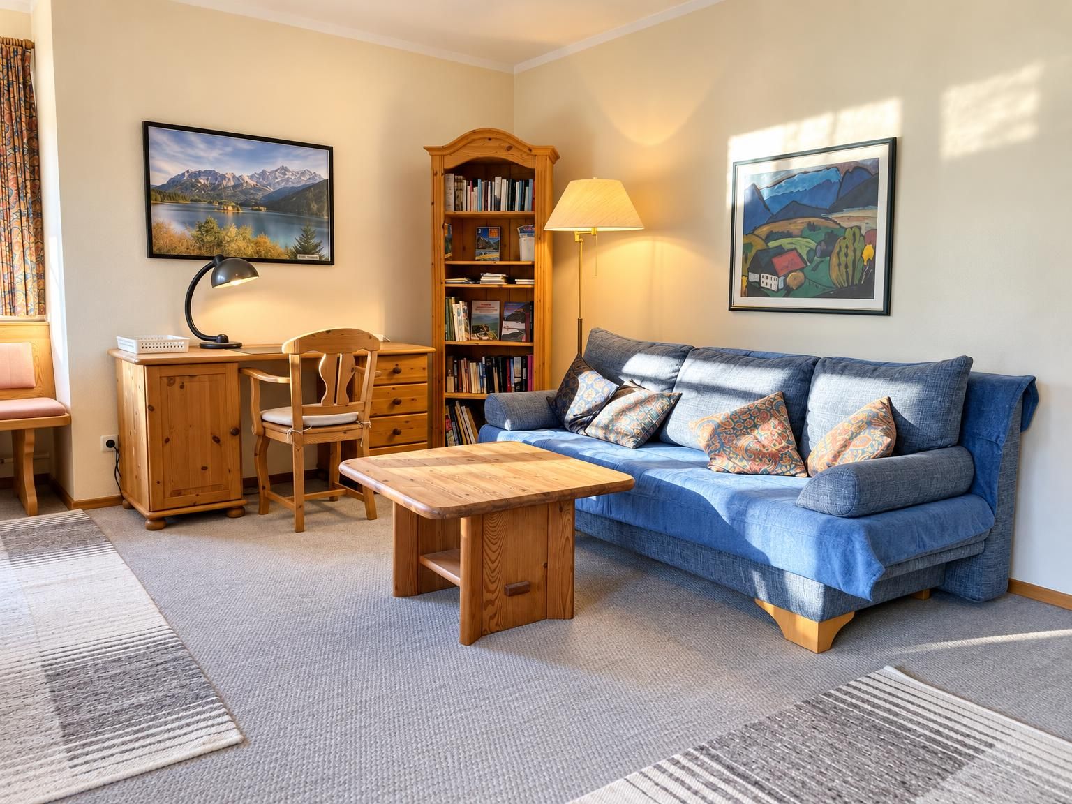 Ein gemütliches Wohnzimmer mit einem blauen Sofa, einem Holztisch und einem Bücherregal.