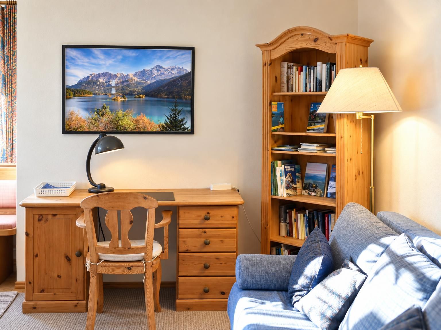 Ein Zimmer mit Schreibtisch, Stuhl, Bücherregal und einer Couch.