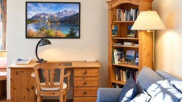 Ein Zimmer mit Schreibtisch, Stuhl, Bücherregal und einer Couch.