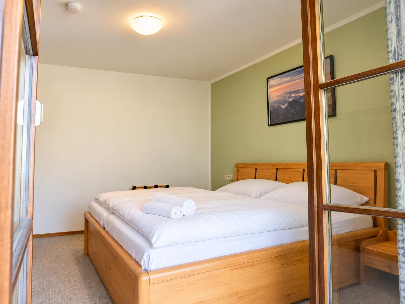 A single bed with a wooden headboard, a bedside table, and a wall-mounted picture.