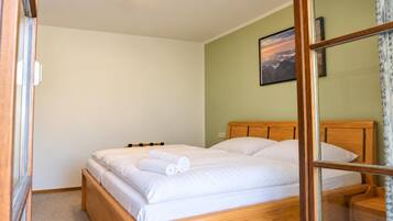 A single bed with a wooden headboard, a bedside table, and a wall-mounted picture.