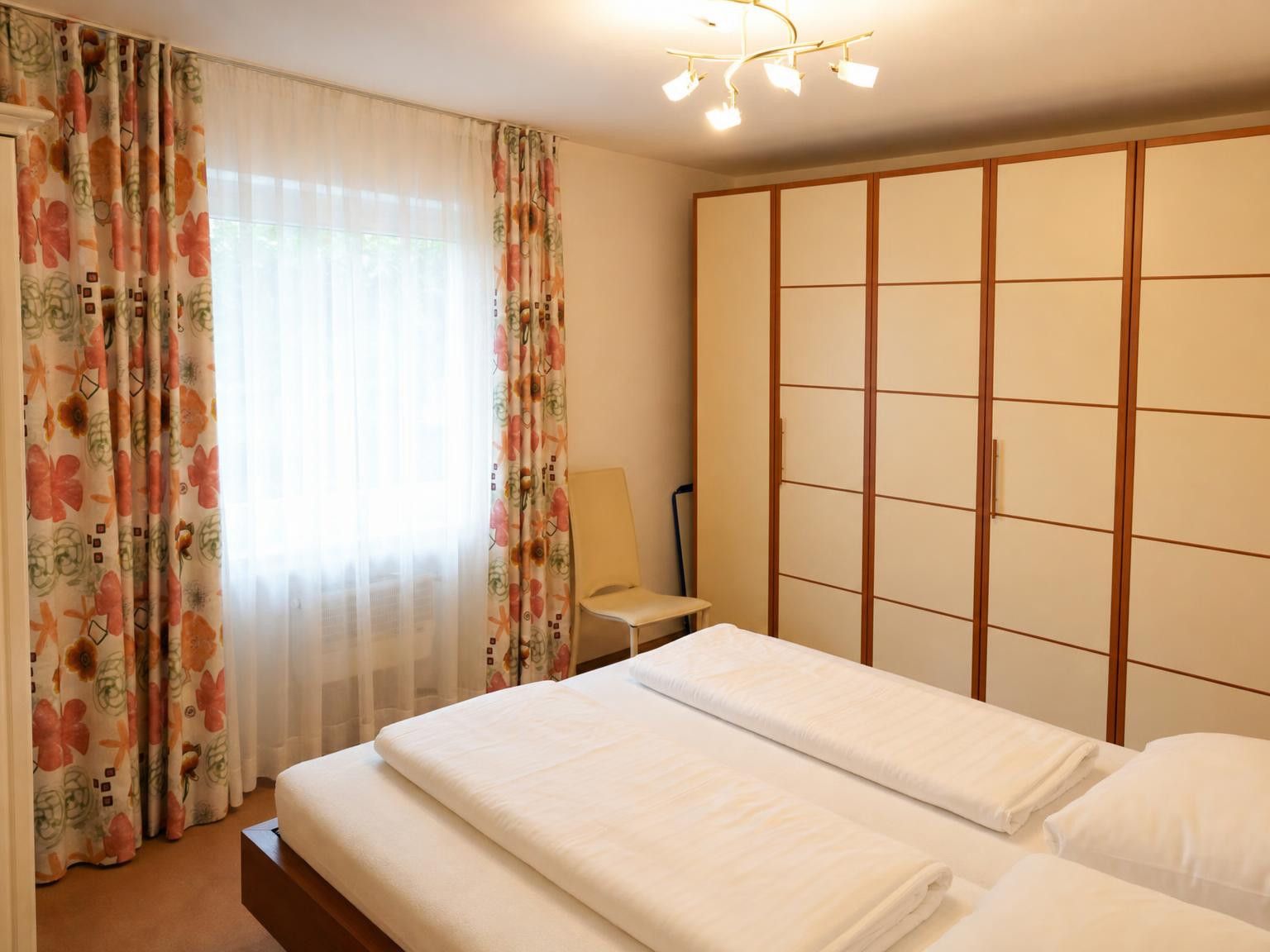 Habitació d'hotel amb un llit, una taula de nit, una làmpada i un armari.