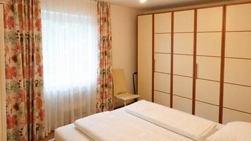A hotel room with a bed, a bedside table, a lamp, and a wardrobe.