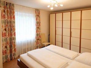 Una habitación de hotel con una cama, una mesita de noche, una lámpara y un armario.