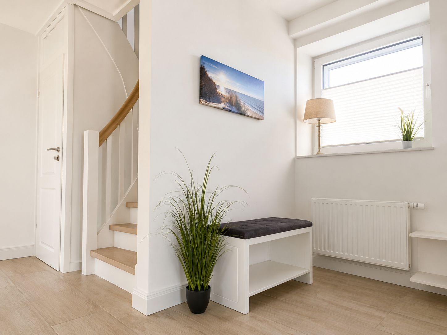 Eine Treppe mit Sitzbank, einer Topfpflanze, einem Gemälde, einer Lampe und einem Fenster mit Jalousien.
