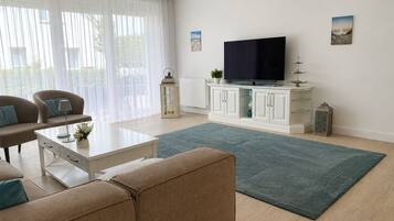 Ein modernes Wohnzimmer mit einem Flachbildfernseher, einem weißen Schrank und einem blauen Teppich.