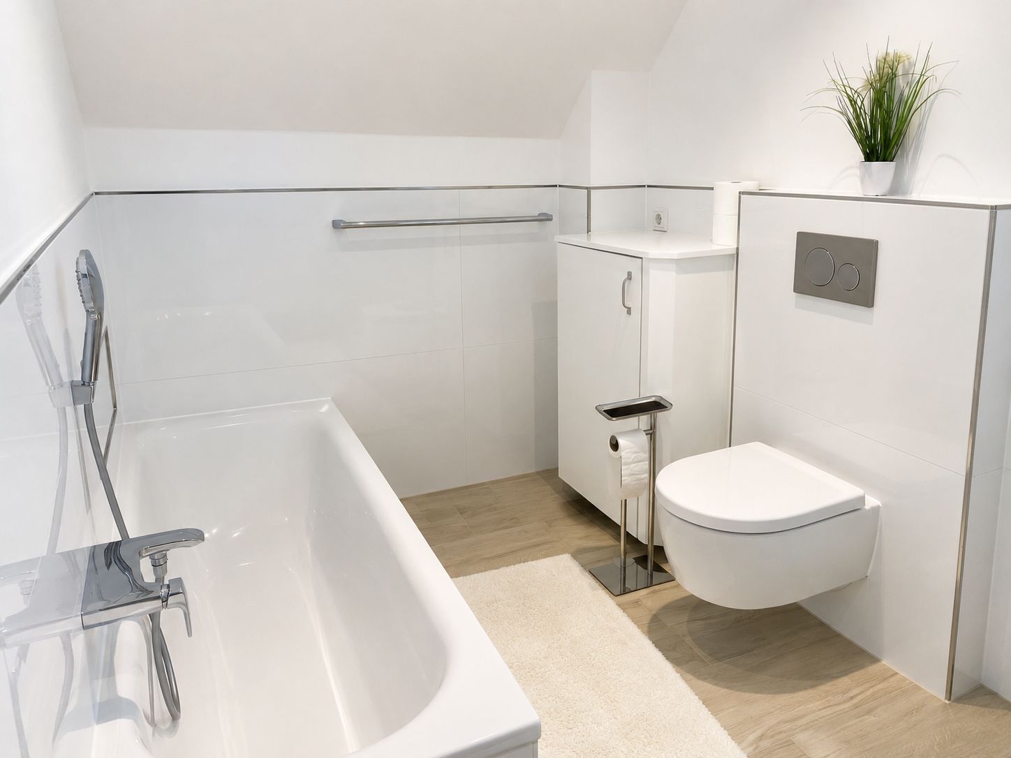 Et moderne badeværelse med badekar, toilet og en lille plante på væggen.