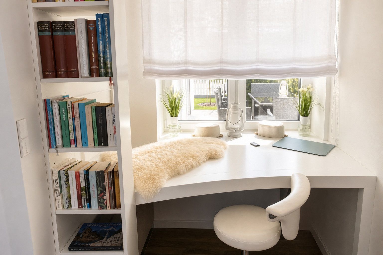 A study with a white desk, bookshelves, a white chair, a window with curtains, and a view of the outdoors.