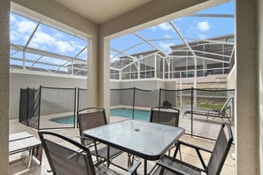 A covered outdoor area with a pool, seating, and a view of the building. - ChampionsGate Townhome w/ Private Pool (Kissimmee)