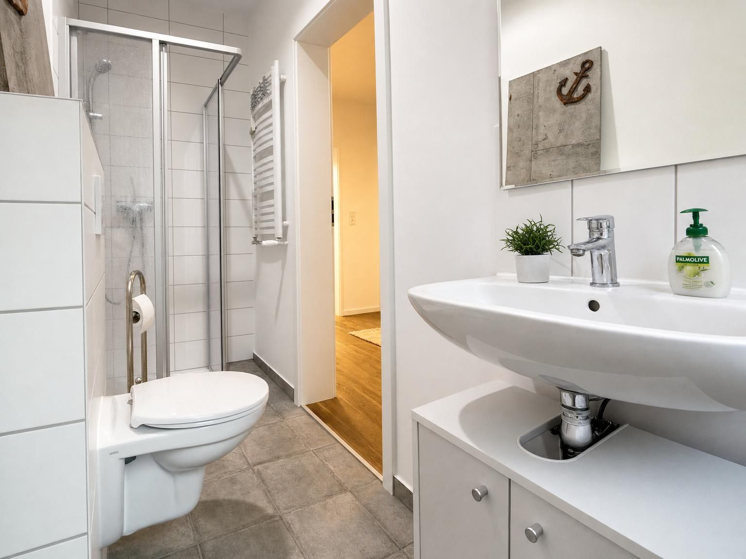 Ein modernes Badezimmer mit Dusche, Toilette, Waschbecken und einem kleinen Topfpflanzen.