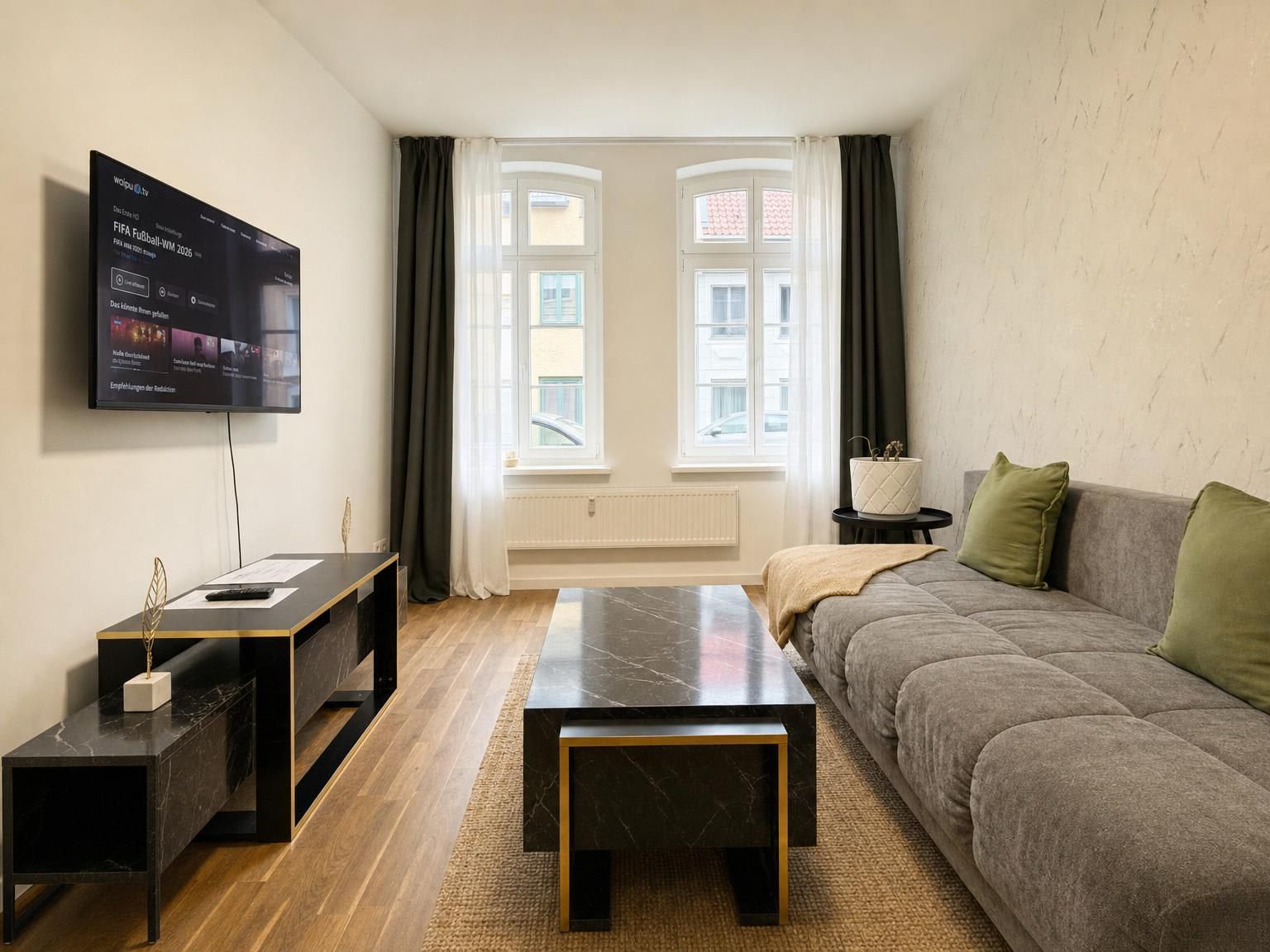 Ein modernes Wohnzimmer mit einer Couch, einem Couchtisch und einem an der Wand befestigten Fernseher.