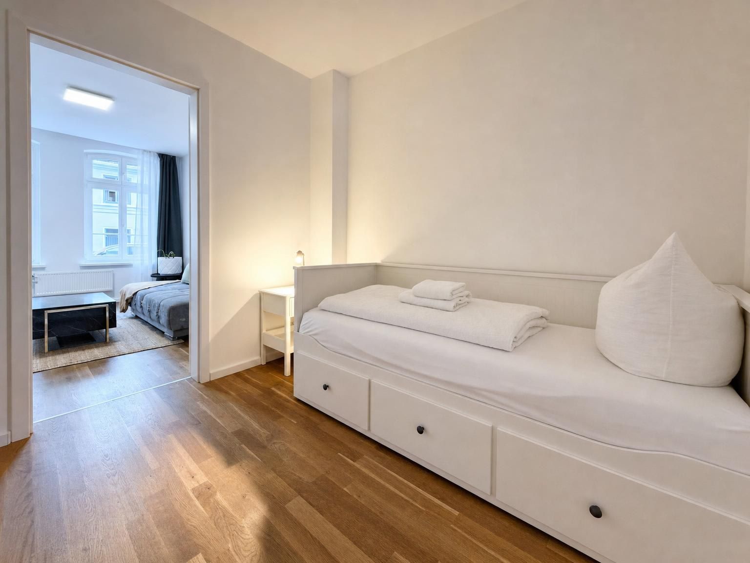 Ein Schlafzimmer mit einem Bett, Nachttischen und Blick auf einen anderen Raum.