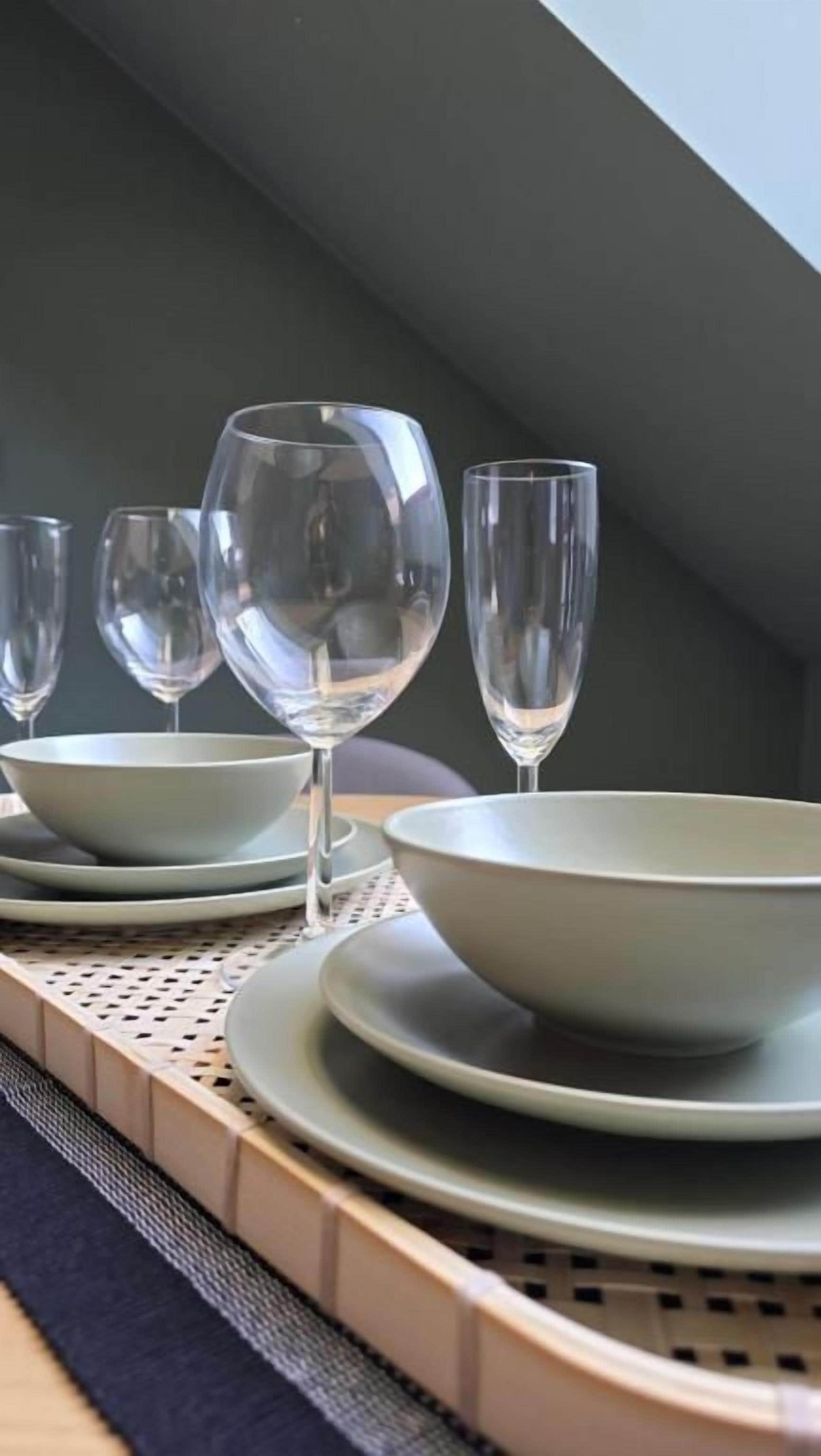 A dining area with a table set for four, featuring clear glassware and plates.