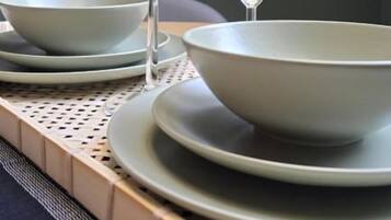 A dining area with a table set for four, featuring clear glassware and plates.