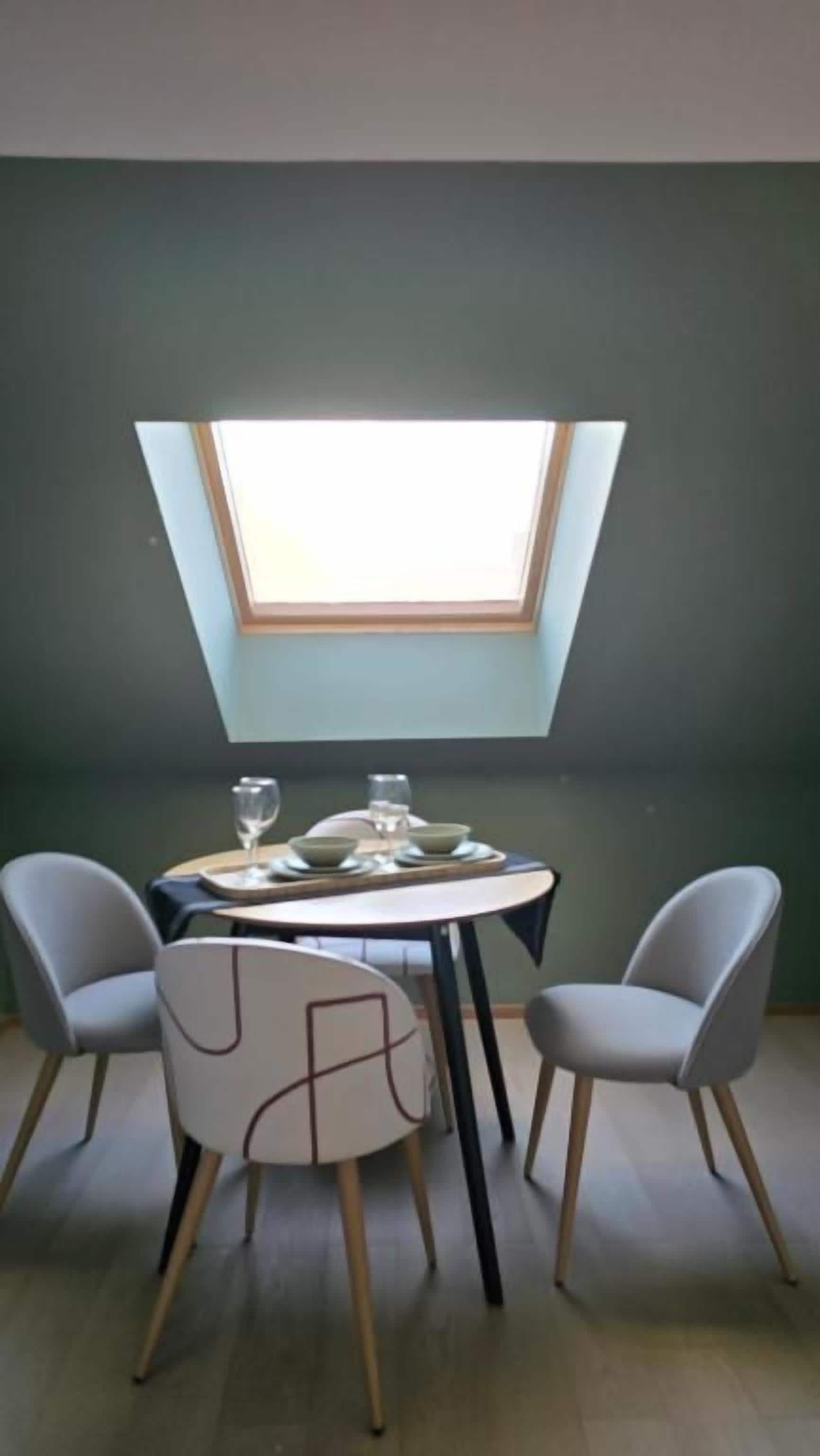 A dining area with a round table, four chairs, and a skylight above.