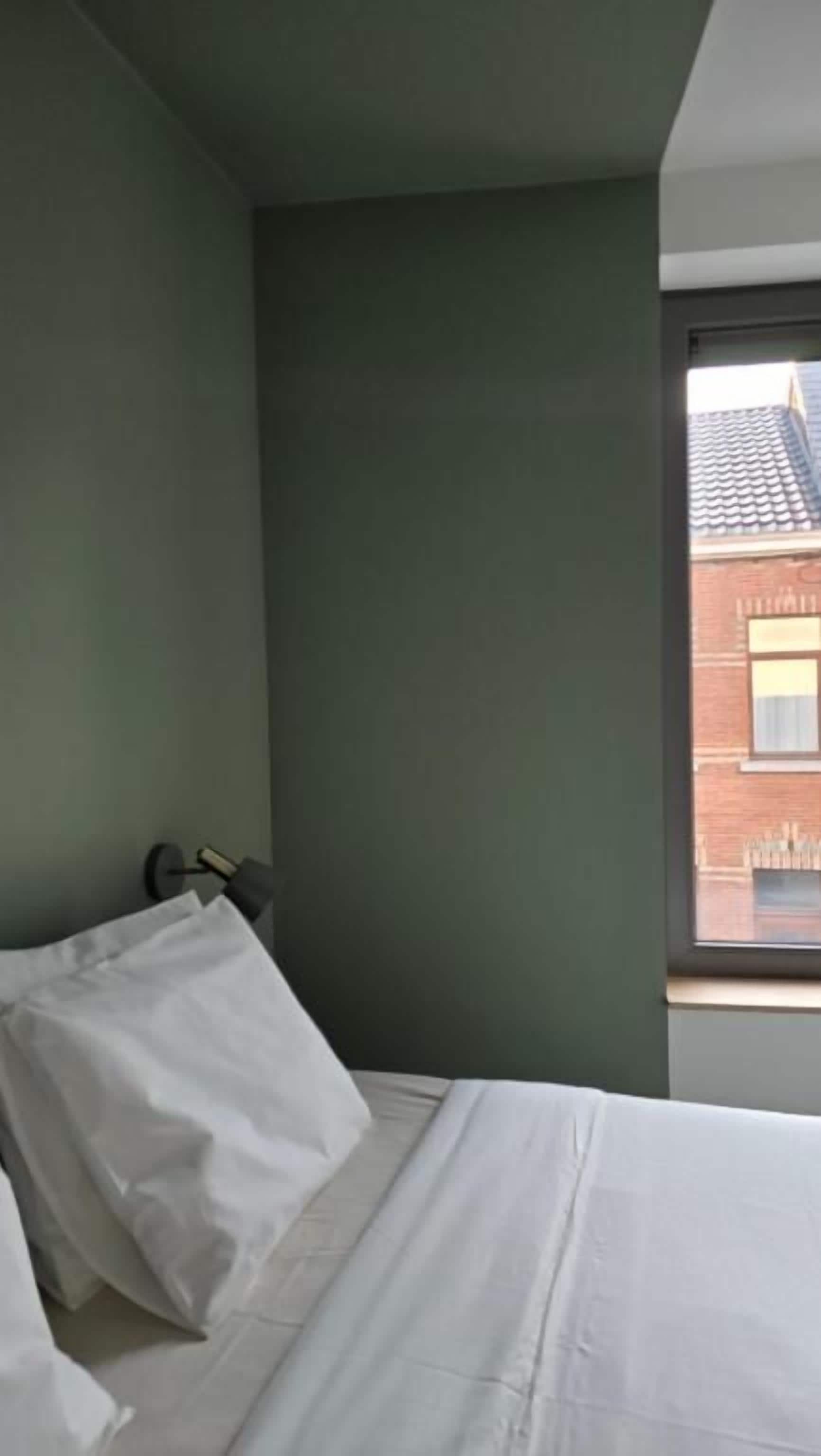 Une chambre d’hôtel avec un lit, une fenêtre et une vue sur un bâtiment situé à l’extérieur.