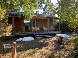 Eine Holzhütte mit einer Veranda, einer Tür und einem Schild mit der Aufschrift 'Estacionamiento'.