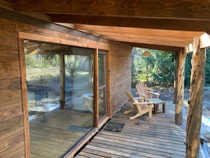 Eine Holzterrasse mit Glastüren, die zu einem Außenbereich mit Sitzgelegenheiten führt.