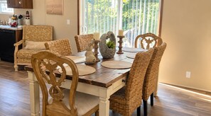 A dining area with a wooden table, woven chairs, and decorative items. - Foley Retreat | 4 Bedrooms • Grill & Smoker (Foley)