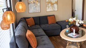 A modern living room with a sectional sofa, decorative pillows, a glass coffee table, and wall art. - Foley Retreat | 4 Bedrooms • Grill & Smoker (Foley)