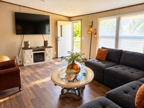 Una sala de estar con televisor de pantalla plana, chimenea, sofá y mesa de centro.