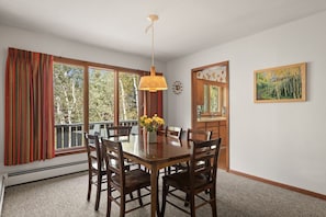 A dining area with a wooden table, chairs, a vase with flowers, and a hanging light fixture. - Cozy Retro Aspen Home, 5 Min to Downtown & Trails (Aspen)