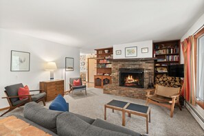 A living room with a fireplace, a sofa, a coffee table, and a bookshelf. - Cozy Retro Aspen Home, 5 Min to Downtown & Trails (Aspen)