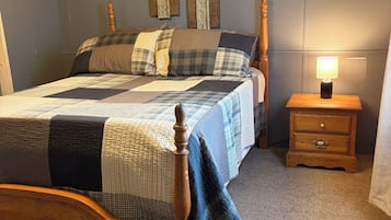 A bedroom with a wooden bed, a nightstand with a lamp, and decorative wall panels.