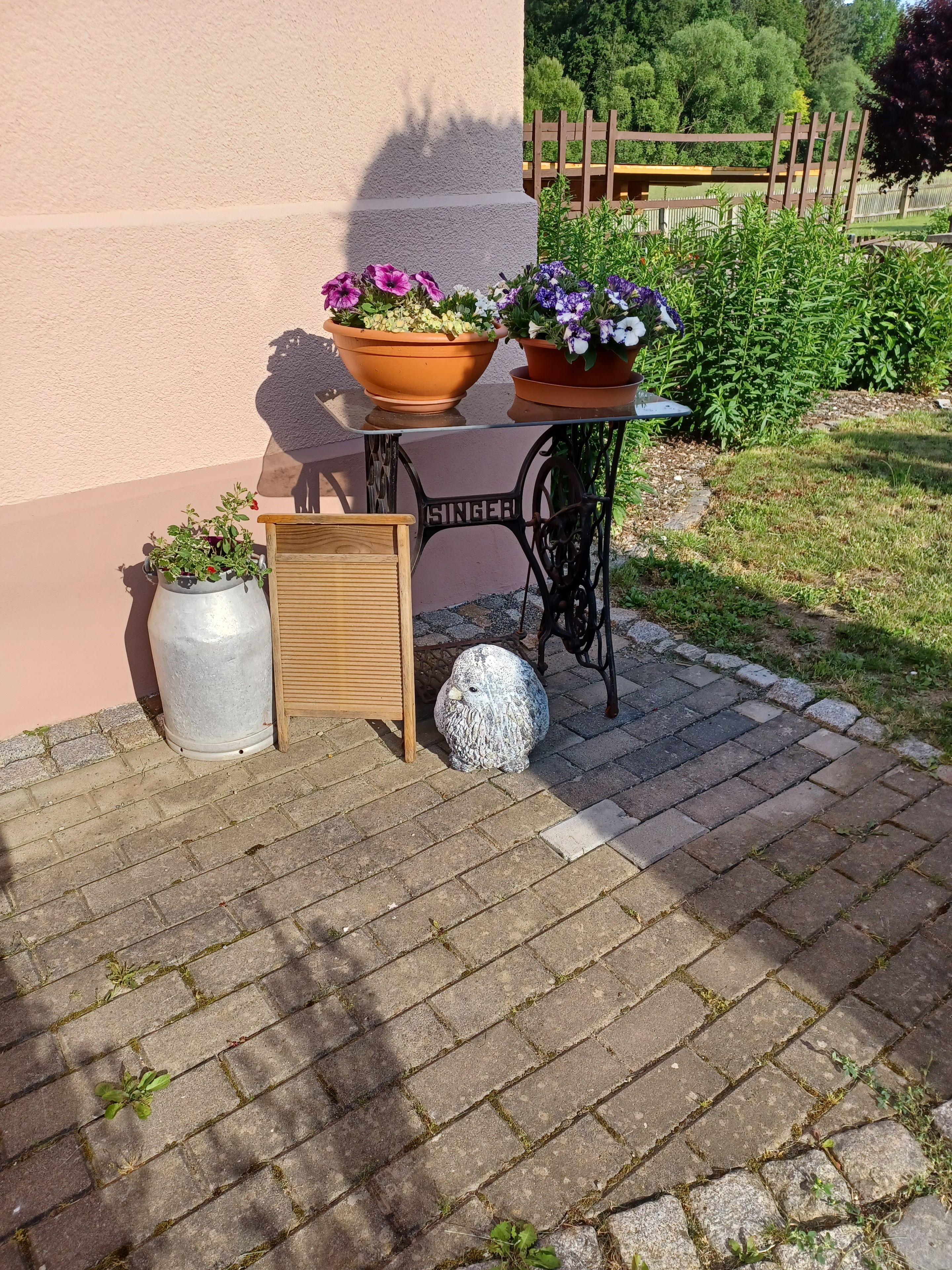 A patio with a table, chairs, potted plants, and a decorative owl statue.