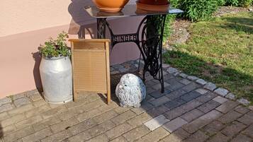 A patio with a table, chairs, potted plants, and a decorative owl statue.