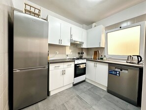 A modern kitchen with stainless steel appliances, white cabinetry, and a large window. - Great 2BR Apartment with 4 min walk everywhere (Playa San Juan)