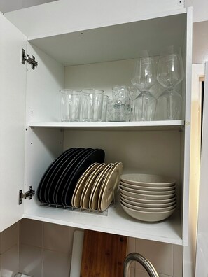 A kitchen cabinet with shelves holding various glassware and plates. - Great 2BR Apartment with 4 min walk everywhere (Playa San Juan)