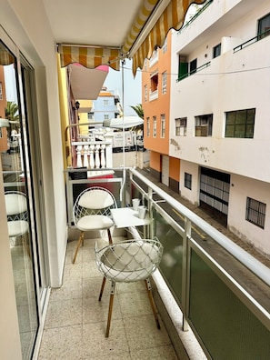 A narrow balcony with a table and chairs, a railing, and a view of colorful buildings. - Great 2BR Apartment with 4 min walk everywhere (Playa San Juan)