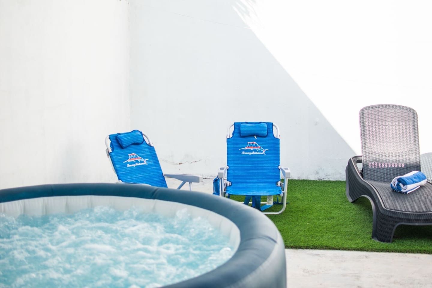 Un jacuzzi con dos sillones reclinables azules y una silla de mimbre.