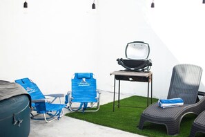 A patio area with a barbecue grill, two blue lounge chairs, and a wicker chair. - Casa Inn Retreat | Villas Morelos II (Puerto Morelos)