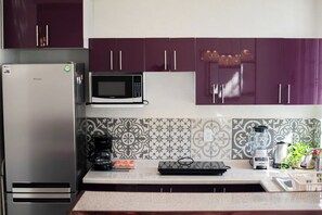 Eine Küche mit Kühlschrank, Mikrowelle, Kaffeemaschine und Mixer auf der Arbeitsfläche.