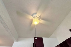 A ceiling fan with a light fixture in a room with white walls and a dark-colored object at the bottom. - Casa Inn Retreat | Villas Morelos II (Puerto Morelos)