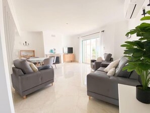 Ein modernes Wohnzimmer mit zwei grauen Sofas, einem Couchtisch und einer großen Grünpflanze.