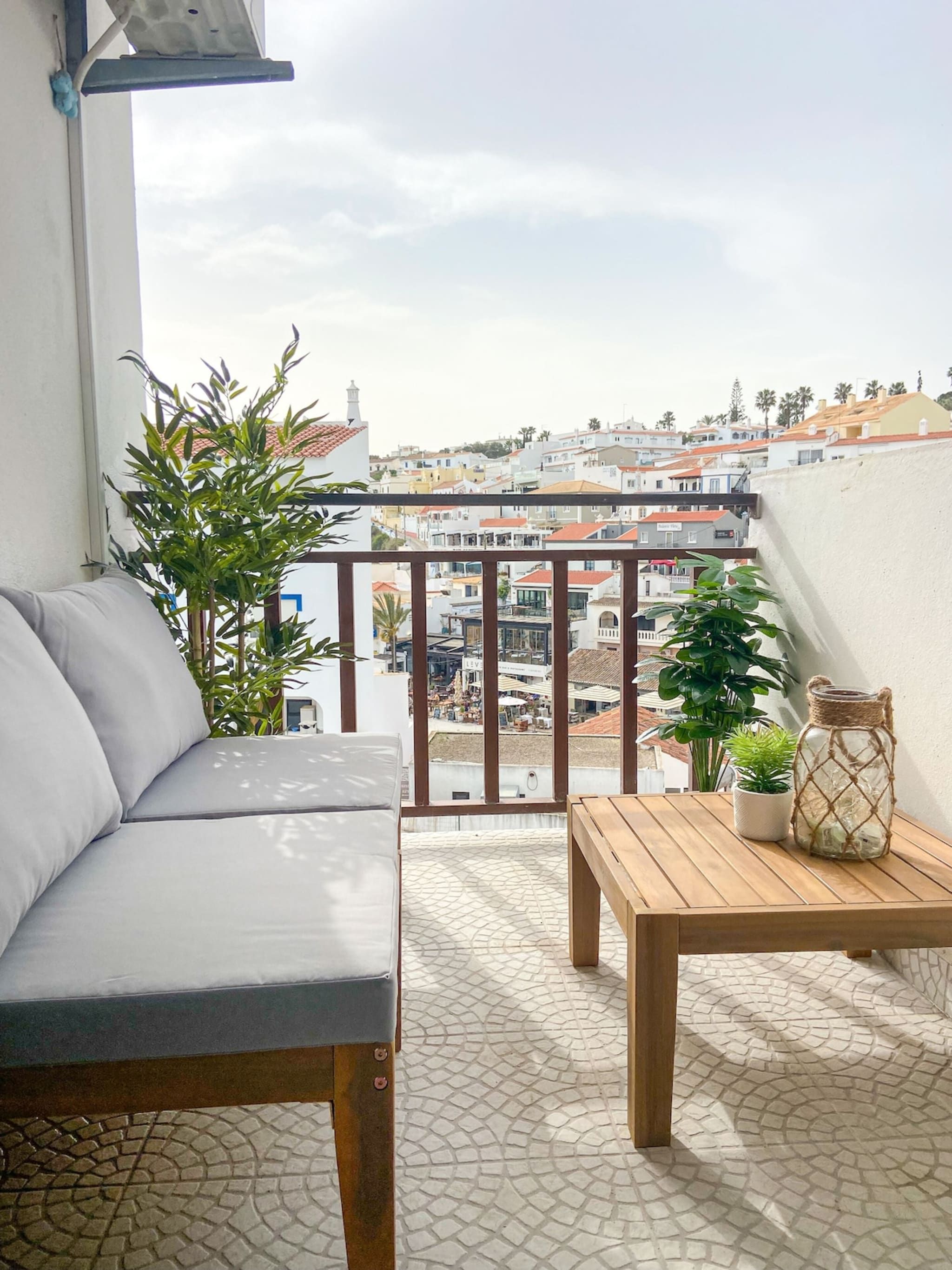A balcony with a sofa, a table, and potted plants.