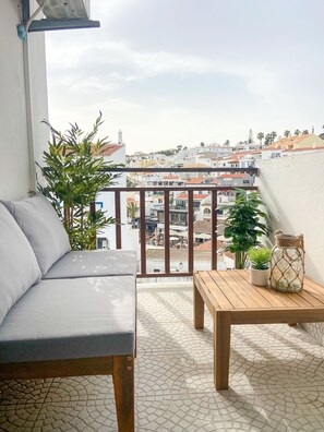 A balcony with a sofa, a table, and potted plants. - Carvoeiro Beach House (Carvoeiro)