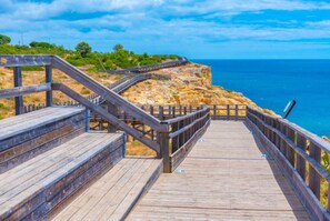 A wooden boardwalk leading to a cliff overlooking the sea. - Carvoeiro Beach House (Carvoeiro)