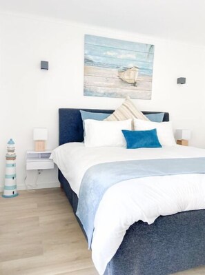 A bedroom with a bed, a nightstand, a lamp, a wall-mounted artwork, and a decorative lighthouse. - Carvoeiro Beach House (Carvoeiro)