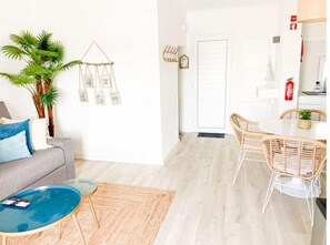 A modern living room with a sofa, a coffee table, and a dining area with chairs. There is a plant and wall art. - Carvoeiro Beach House (Carvoeiro)