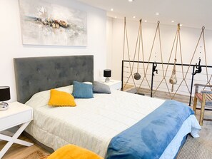 A modern bedroom with a large bed, a bedside table, a hanging swing, and a painting on the wall. - Casa Eden (Ferragudo)