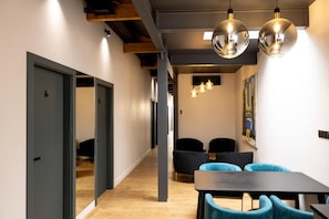 A modern interior with a wooden floor, a dark table with chairs, and pendant lighting.