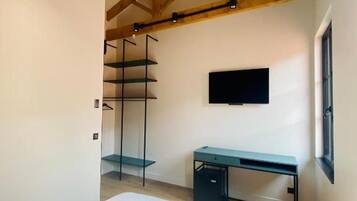 Une chambre à coucher avec un lit, un bureau, une télévision et une armoire.