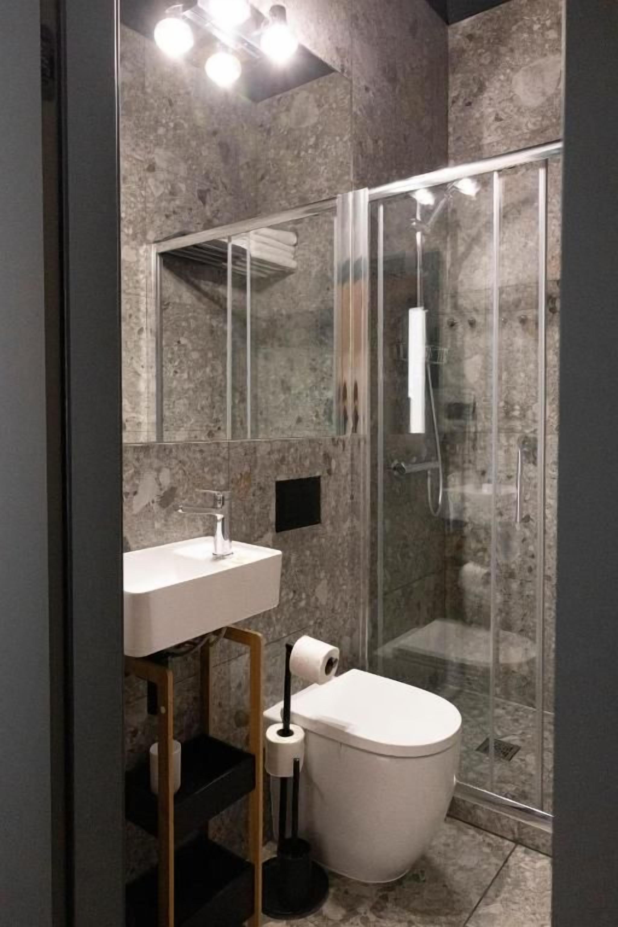 Ein modernes Badezimmer mit Duschkabine aus Glas, Waschbecken mit Spiegel und Toilette.