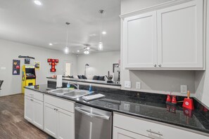 A modern kitchen with a stainless steel dishwasher, double sink, and a marble countertop. - Double T Rally House - 3BR/3BA - Walk to Tech (Lubbock)