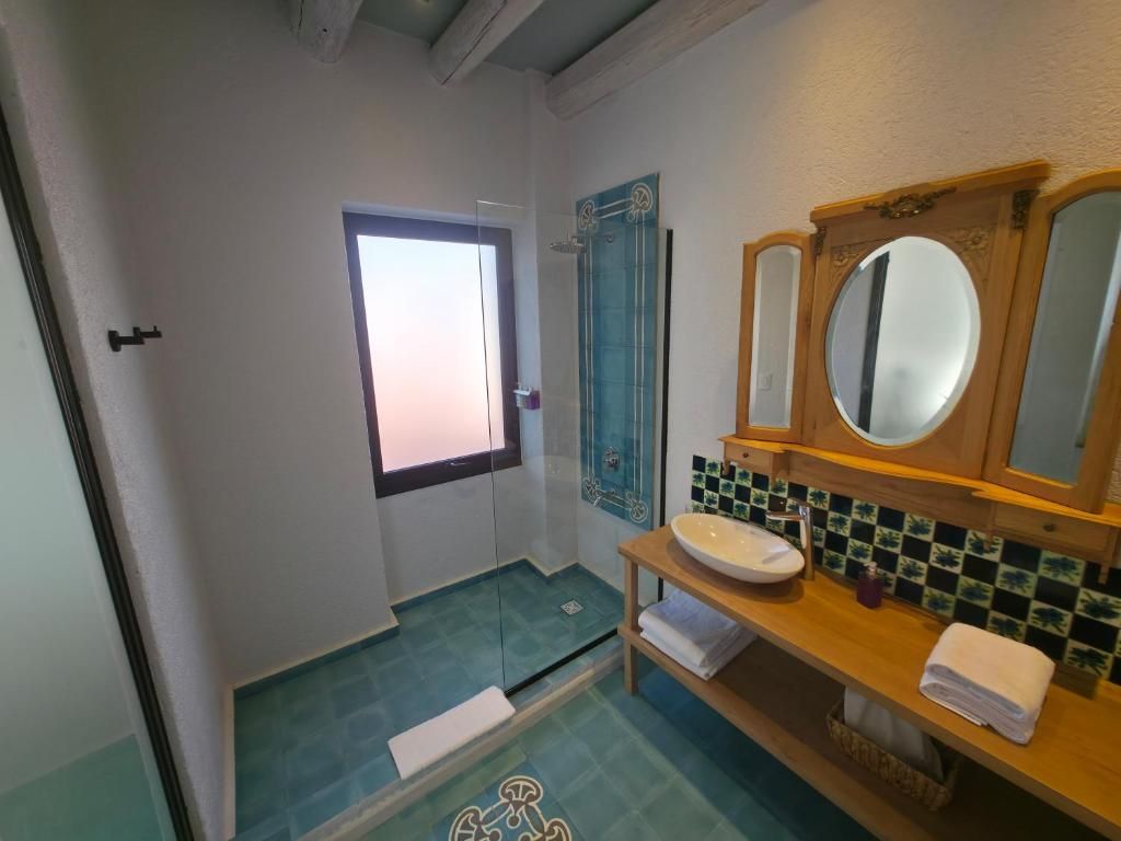 Un baño con ducha, lavabo, espejo y toallero.